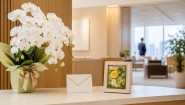 役員室の受付に胡蝶蘭と小型の花フレームを並べた就任祝いの選択イメージ