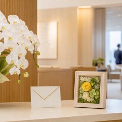 役員室の受付に胡蝶蘭と小型の花フレームを並べた就任祝いの選択イメージ