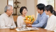 両親の金婚式に子どもたちから黄色とオレンジの花束を贈る家族のイメージ