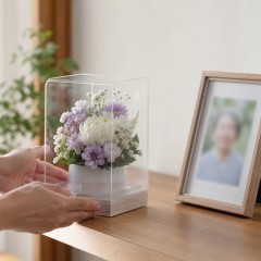 静かな自宅で小さなお供え花を思い出の写真のそばに置くイメージ