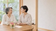 敬老の日に母娘が小さな花とカードを囲んで話すイメージ