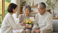 敬老の日に祖父母二人へ一つの花を贈る一般的な家族の場面