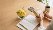 カレンダーと荷物を見ながら花ギフトの到着日を確認する様子