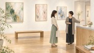 ギャラリーの受付で、作家と来場者がお祝いの花の置き場所を相談する様子