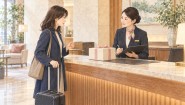 ホテルのフロントで、旅行者がスタッフにギフトの受け取りを相談する様子